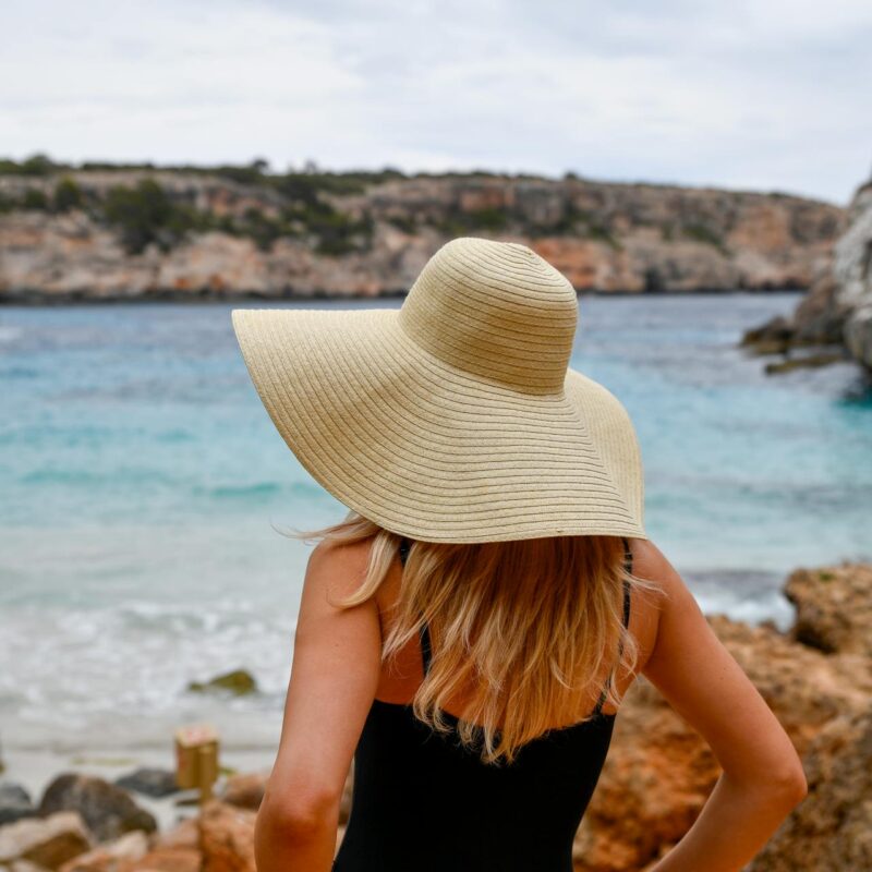 Paní v klobouku u moře na dovolené